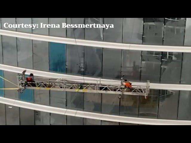 High winds cause workers to swing on scaffolding