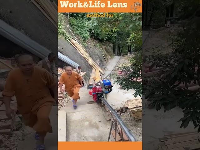 A man uses a petrol-powered monorail to transport logs uphill, walking alongside concrete stairs.