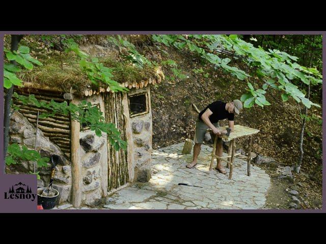 Shelter for survival in the forest. Construction of a house near a stream