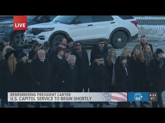 Carter family walks alongside horse-drawn carriage | Honoring President Jimmy Carter