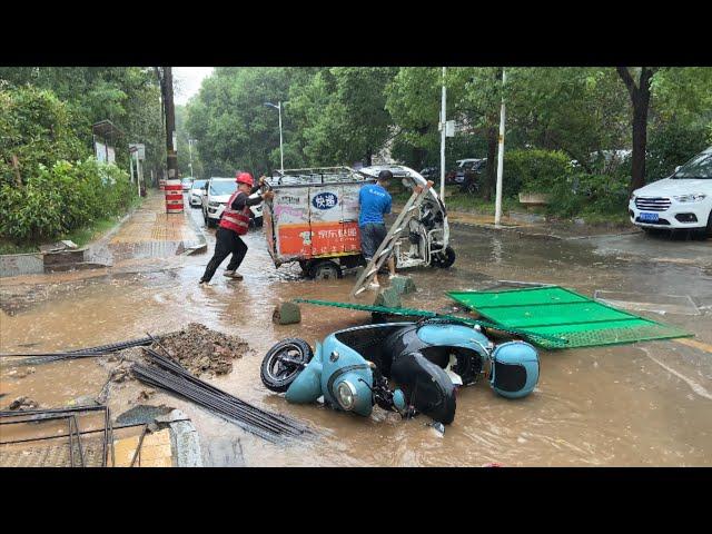 暴雨天散步 快递小哥的三轮车陷入水坑中