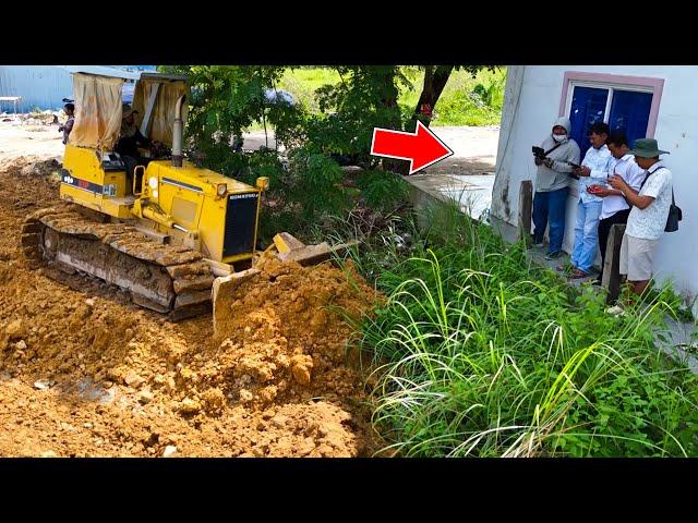 Good bulldozer operator pushing soil and filling land with dump trucks