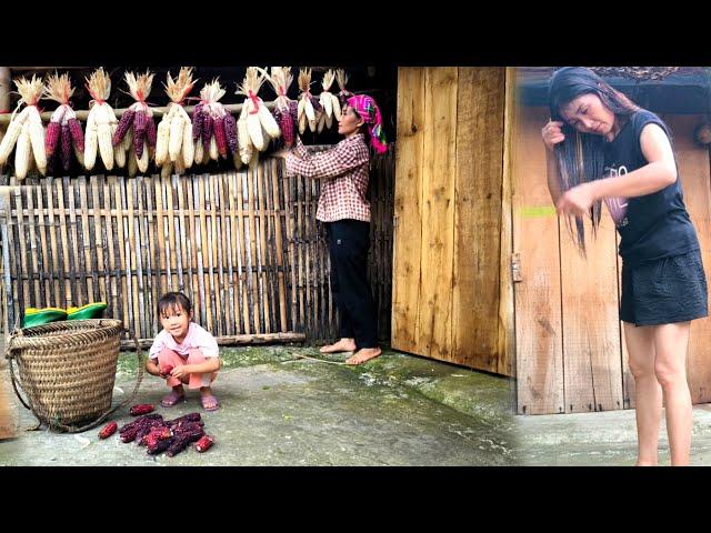 Mother and daughter bundle corn into bunches and hang them on the wall to dry naturally,storing food