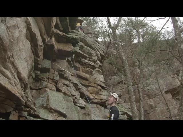 Climber, wearing a helmet, gets hit on the head with a rock.