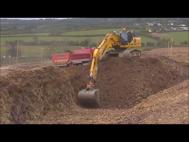 Komatsu PC490 excavator loading trucks on a road construction site