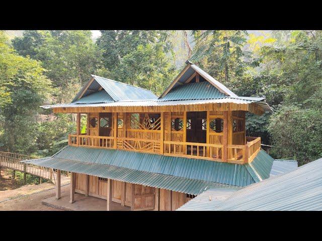 Spray painting the second floor of a wooden house - building a wooden house in the forest