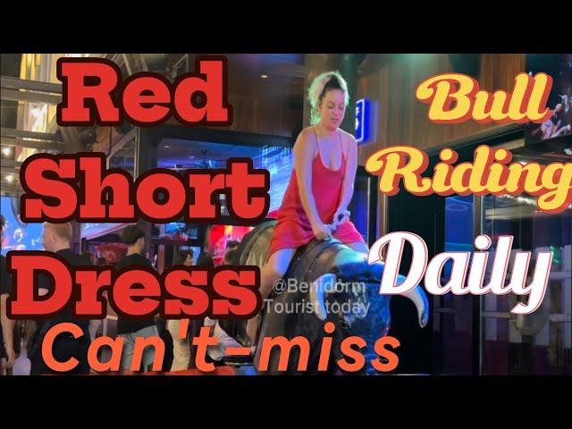 Red short dress Girl ️ bull  riding in Benidorm Spain ! Mechanical bull  riding! Benidorm bull