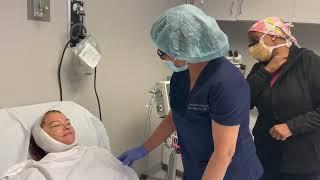 Facelift patient in recovery with nurse who monitors her as she awakens from sedation.