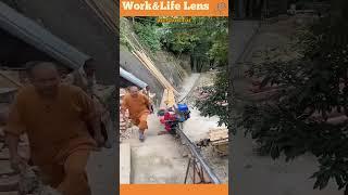 A man uses a petrol-powered monorail to transport logs uphill, walking alongside concrete stairs.