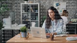 Young woman employee working with laptop in office doing work in internet