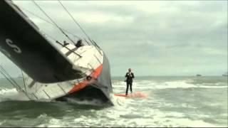 Alex Thomson debout, en mer, sur la quille de son bateau