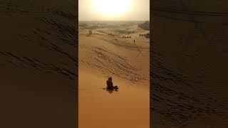 Sled riding down a sand dune in the Sahara Desert