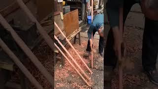 Rural carpenter carving round wood stick with simple tool