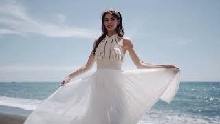 Stunning bride twirls joyfully on a sandy beach, her handmade Atelier Zolotas wedding gown.