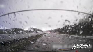 Car skids backwards on motorway during severe weather, narrowly avoiding traffic officer