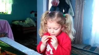 A sweet little girl is eating a bitter lemon