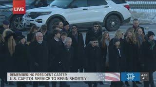 Carter family walks alongside horse-drawn carriage | Honoring President Jimmy Carter