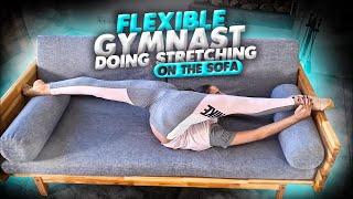 Home contortion. Flexible gymnast doing stretching on the sofa. Flexshow