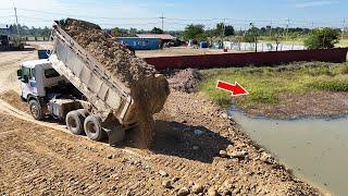 Awesome bulldozer pushing soil with dump trucks filling over the farm