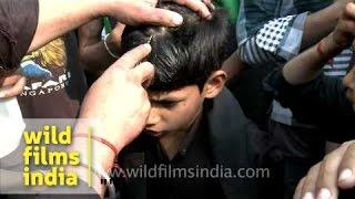 Young Shiite Muslim boy cries as an elder makes a cut on his forehead during Muharram