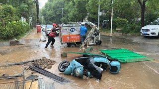 暴雨天散步 快递小哥的三轮车陷入水坑中