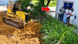 Good bulldozer operator pushing soil and filling land with dump trucks