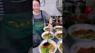 The lady is using hot oil to stimulate the aroma of chili peppers. This spinach noodle is delicious