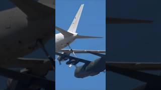 KC-767 refuels a C-130 in mid-air. The dense formation of large aircraft creates a sense of urgency