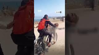 شاب ينقل جثمان والده على دراجة هوائية، بعد إصابته برصاص الاحتلال، أثناء محاولته الحصول على المساعدات