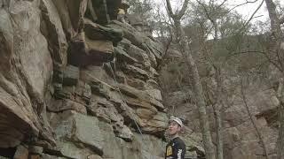 Climber, wearing a helmet, gets hit on the head with a rock.