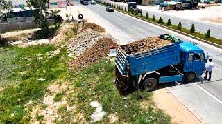 Small Machinery Filling New Land With Rock. Small Dump Trucks Unloading Rock