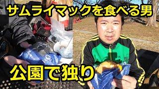 公園で独りサムライマックを食べる男