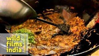 Woman makes fish curry at a Bengali wedding - India