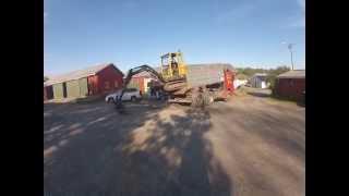 Mini excavator climbing down truck.