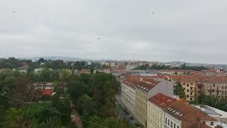 Birds are flying above the rooftops of Brno, Czech Republic. The camera pans across the skyline