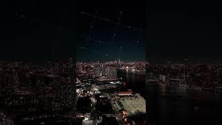 Camera panning upwards revealing New York City skyline at night in a vertical video. The East River