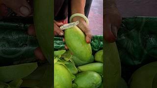 Green mango cut by an old woman at a fruit store